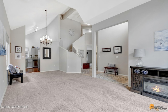 interior space featuring high vaulted ceiling, a notable chandelier, beamed ceiling, carpet, and a glass covered fireplace