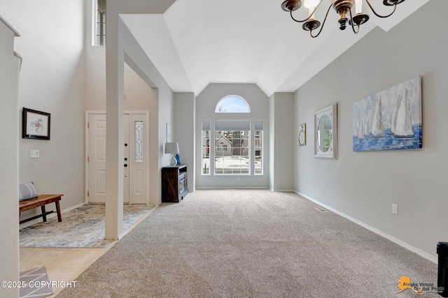 foyer with light carpet, an inviting chandelier, baseboards, and high vaulted ceiling