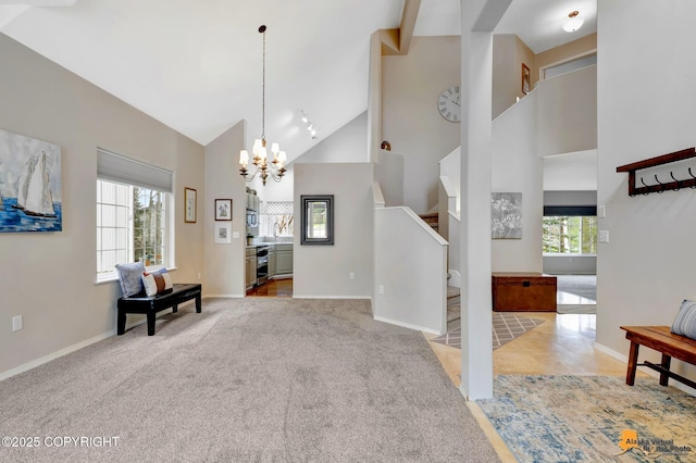 entrance foyer with baseboards, a chandelier, stairway, carpet, and high vaulted ceiling