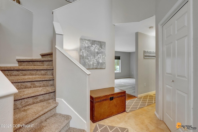 stairway with baseboards and tile patterned floors