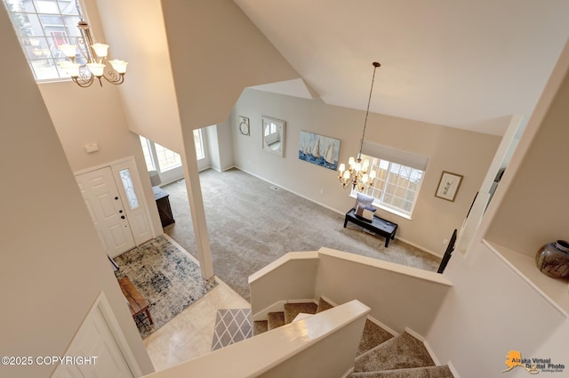 carpeted entrance foyer featuring stairs, high vaulted ceiling, and an inviting chandelier