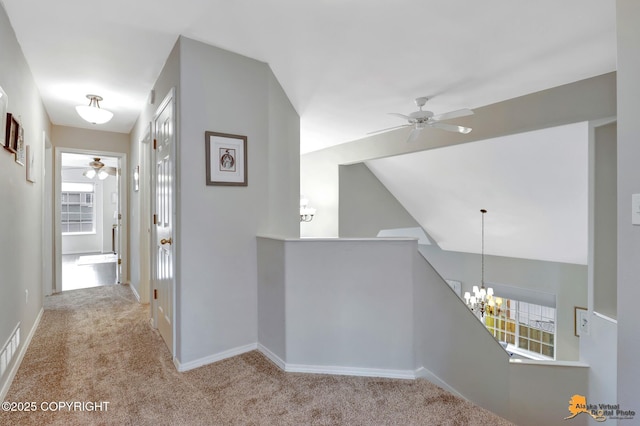 hall featuring an inviting chandelier, carpet flooring, vaulted ceiling, an upstairs landing, and baseboards