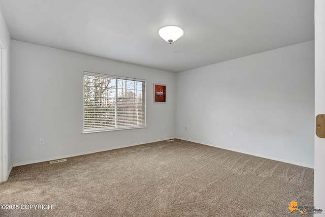 spare room with carpet floors, baseboards, and visible vents