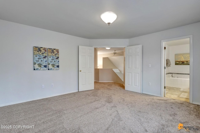 unfurnished bedroom featuring connected bathroom, baseboards, and carpet flooring