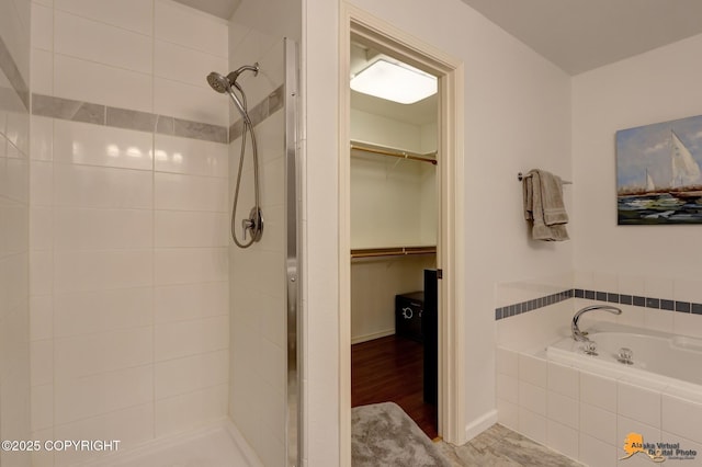 full bath featuring a stall shower, a garden tub, and a walk in closet