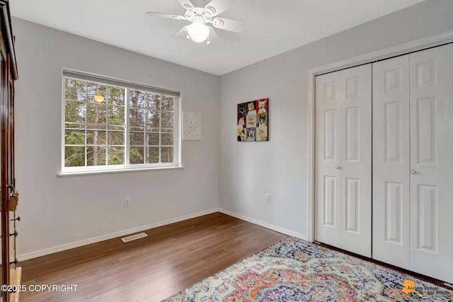 bedroom featuring a closet, visible vents, baseboards, and wood finished floors