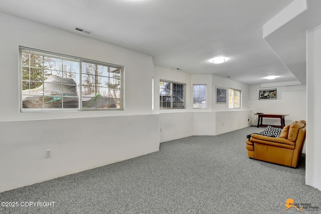 unfurnished room featuring plenty of natural light, carpet, and visible vents