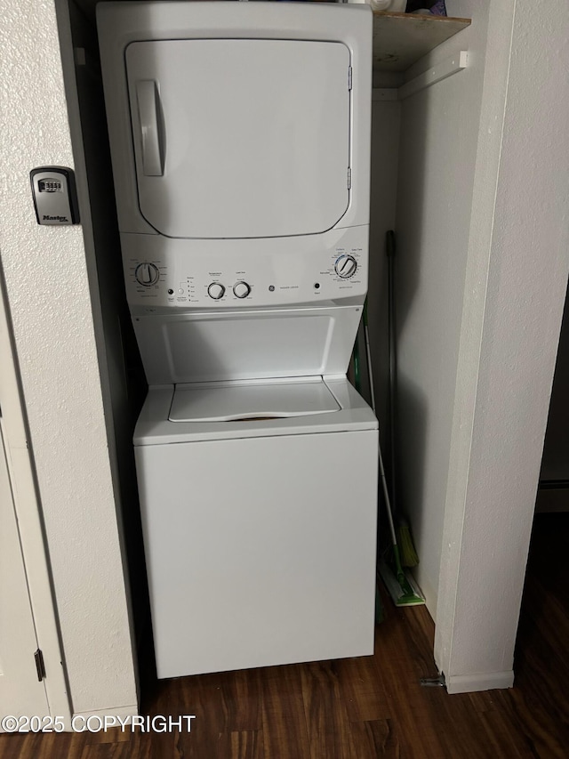 laundry area featuring laundry area, dark wood-type flooring, and stacked washer and clothes dryer