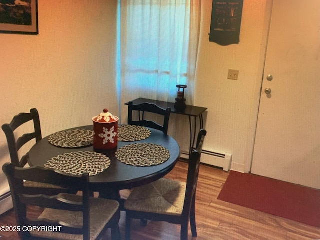 dining space with baseboard heating and wood finished floors