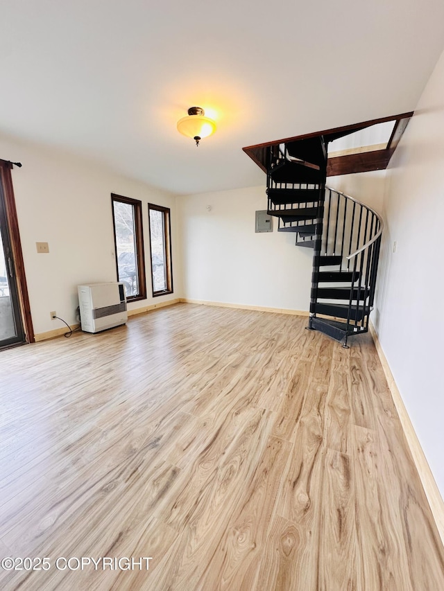 unfurnished living room featuring baseboards, stairway, wood finished floors, and heating unit