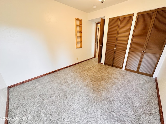 unfurnished bedroom with baseboards, carpet floors, and multiple closets