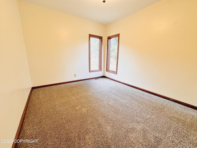 empty room featuring carpet and baseboards