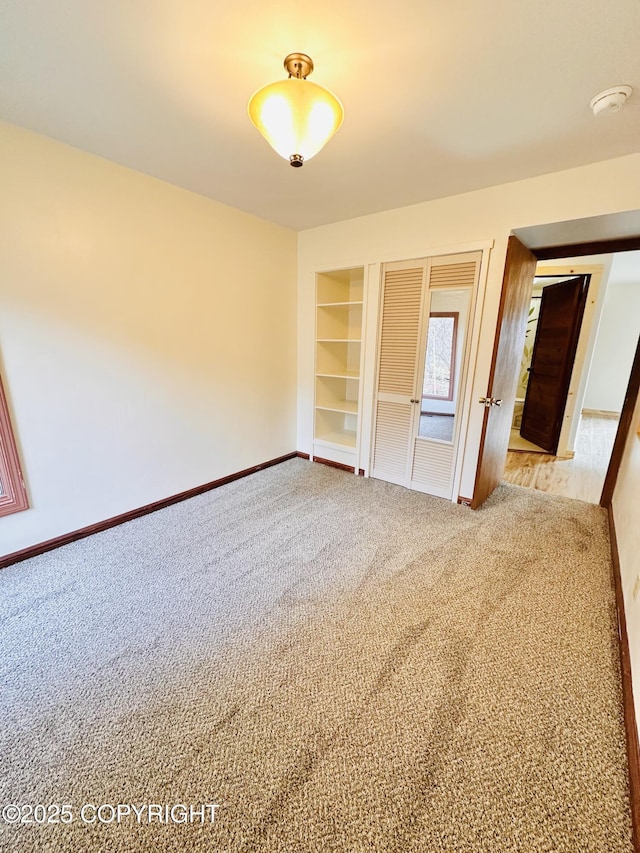 carpeted spare room featuring built in features and baseboards