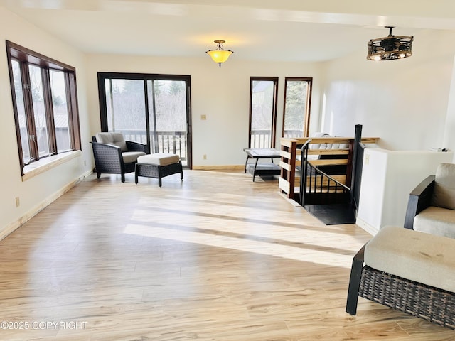 living area with light wood finished floors, an upstairs landing, and baseboards