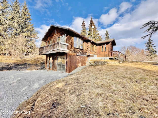 view of property exterior featuring gravel driveway and a deck