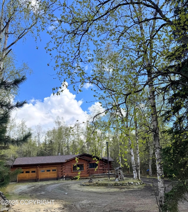 10337 Chain Of Rock St, Eagle River, AK 99577 - view of front of house featuring dirt driveway, log exterior, and a garage