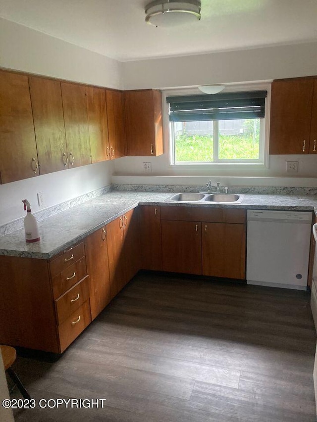 kitchen with brown cabinetry, white dishwasher, dark wood finished floors, and a sink