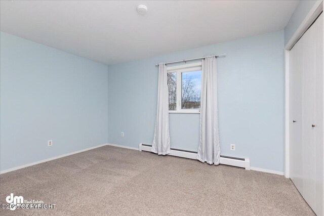 unfurnished bedroom with a closet, baseboards, a baseboard heating unit, and carpet flooring