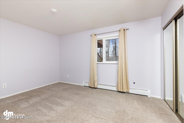 unfurnished bedroom with a baseboard heating unit, baseboards, and carpet floors