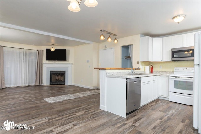 kitchen with dark wood finished floors, a peninsula, white cabinets, appliances with stainless steel finishes, and open floor plan