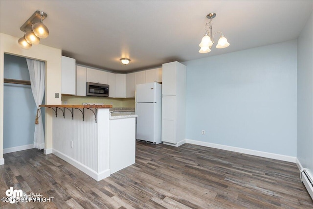 kitchen with stainless steel microwave, a peninsula, freestanding refrigerator, and dark wood-style flooring