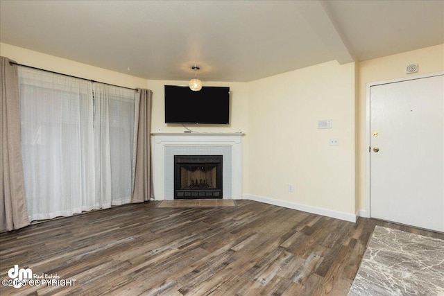 unfurnished living room featuring wood finished floors, baseboards, and a tile fireplace