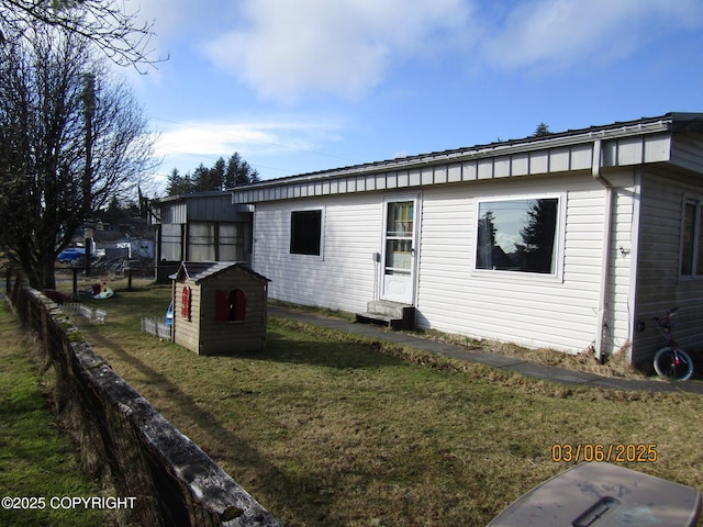 view of front of home with entry steps, a storage shed, an outdoor structure, and a front yard