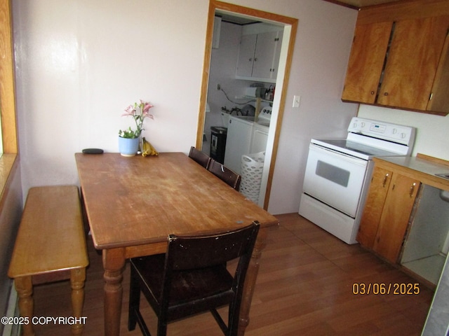 kitchen featuring brown cabinetry, washer and dryer, electric stove, and light wood finished floors