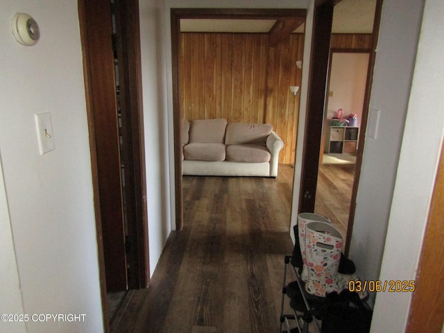 corridor featuring wooden walls, beam ceiling, and wood finished floors