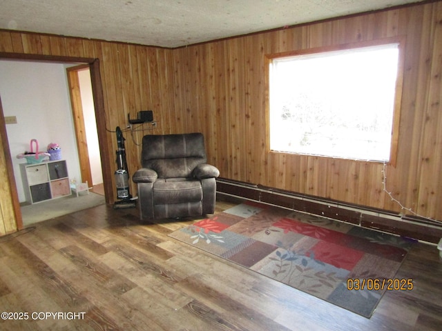 living area featuring a textured ceiling, wooden walls, and wood finished floors