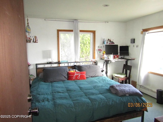 bedroom with multiple windows and a baseboard radiator