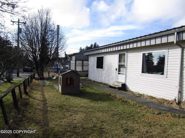 view of home's exterior with a yard, an outdoor structure, and fence