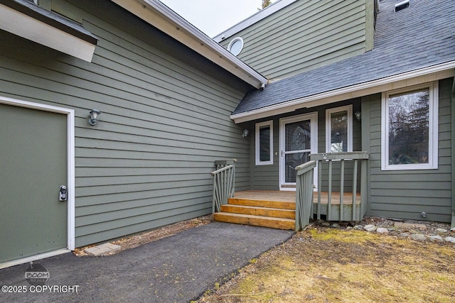 view of exterior entry featuring a shingled roof