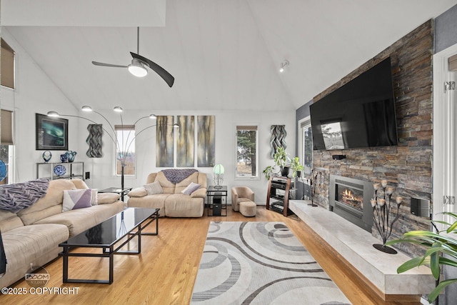 living room featuring a ceiling fan, wood finished floors, a fireplace, and high vaulted ceiling