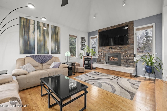 living area featuring high vaulted ceiling, wood finished floors, and a fireplace