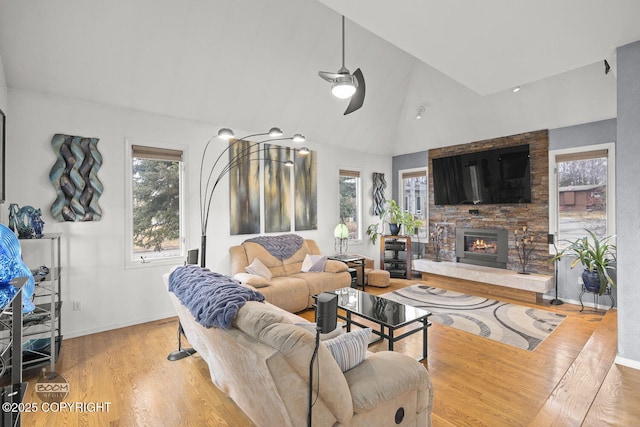 living room with baseboards, a ceiling fan, wood finished floors, and a fireplace