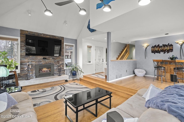 living area with stairway, a dry bar, vaulted ceiling, a fireplace, and wood finished floors