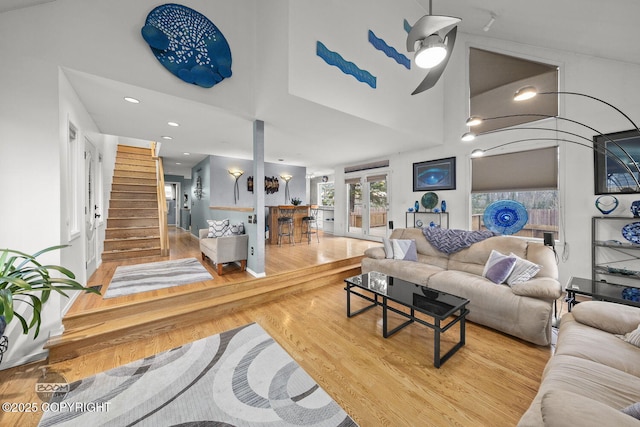 living area featuring stairway, wood finished floors, recessed lighting, french doors, and a towering ceiling