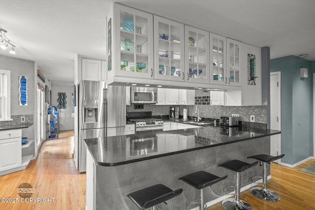 kitchen featuring a sink, white cabinets, tasteful backsplash, and stainless steel appliances