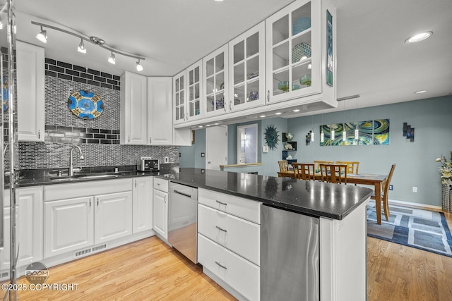 kitchen with visible vents, a sink, decorative backsplash, a peninsula, and stainless steel dishwasher