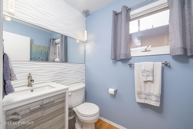 full bathroom featuring toilet, vanity, baseboards, and wood finished floors