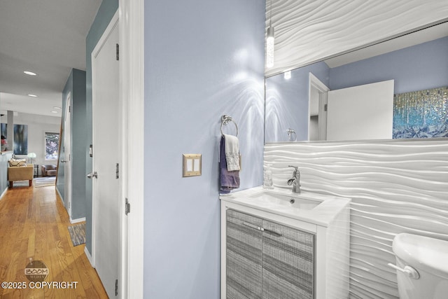 bathroom featuring vanity, toilet, wood finished floors, and recessed lighting