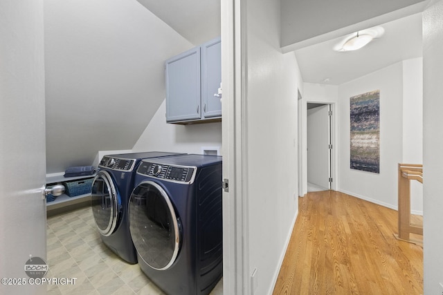 laundry area with washing machine and dryer, cabinet space, baseboards, and light floors