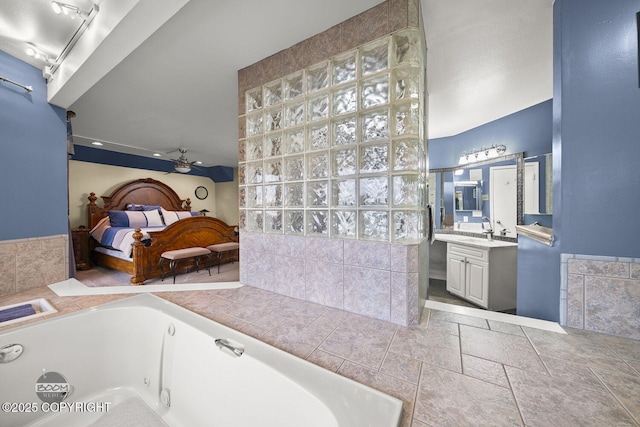 ensuite bathroom with ensuite bath, a tub with jets, ceiling fan, and vanity