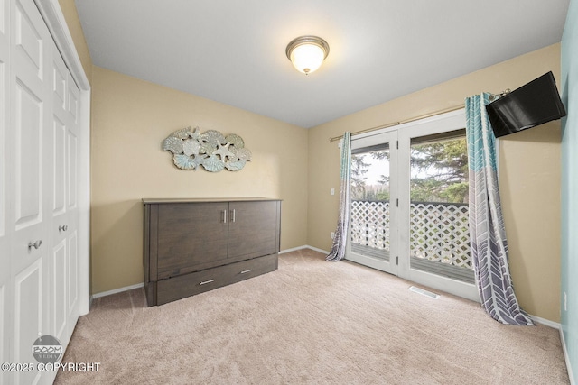 unfurnished bedroom featuring access to exterior, visible vents, baseboards, carpet flooring, and a closet