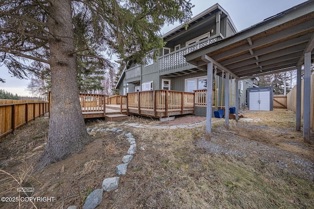 view of yard featuring a deck, an outbuilding, a storage unit, and a fenced backyard