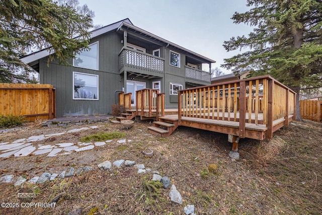 rear view of property with a balcony and fence