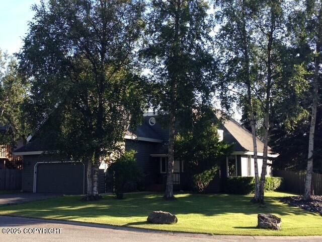 view of front of home featuring a front yard, concrete driveway, fence, and a garage