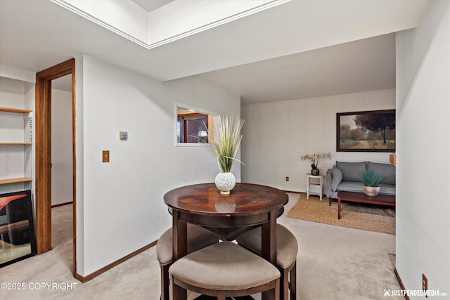 dining space with light carpet and baseboards