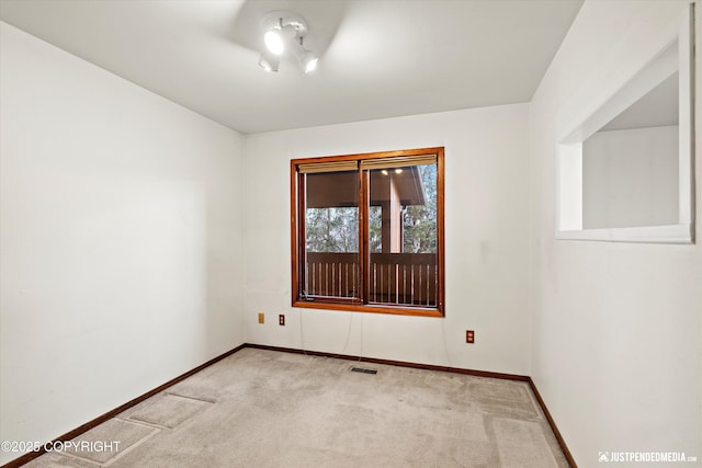 spare room featuring baseboards, visible vents, and light colored carpet